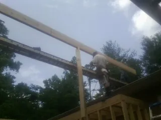 Carpenter setting a ridge beam over a new addition frame — Ice Dam Removal by Roofing Brothers in Beasley
