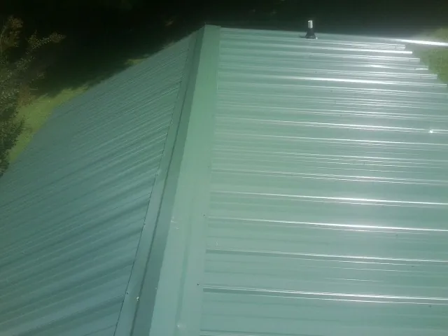 New green metal panels meeting at the ridge of a roof — Flat Roof Repair work by our crew in Beasley