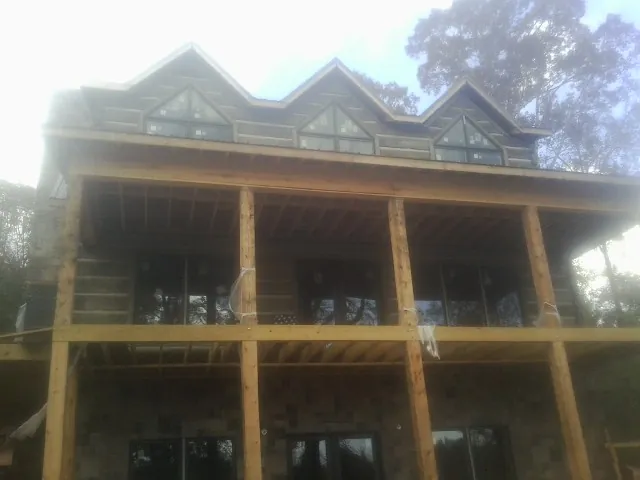 Dormers and porch framing on a large log home under construction — Roof Coating work by our crew in Beasley