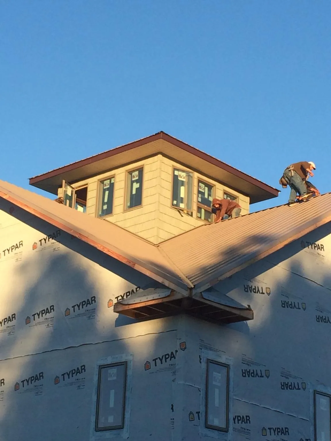 Roofers working around a rooftop cupola on a new metal roof at sunset — Roof Waterproofing in Beasley by Roofing Brothers
